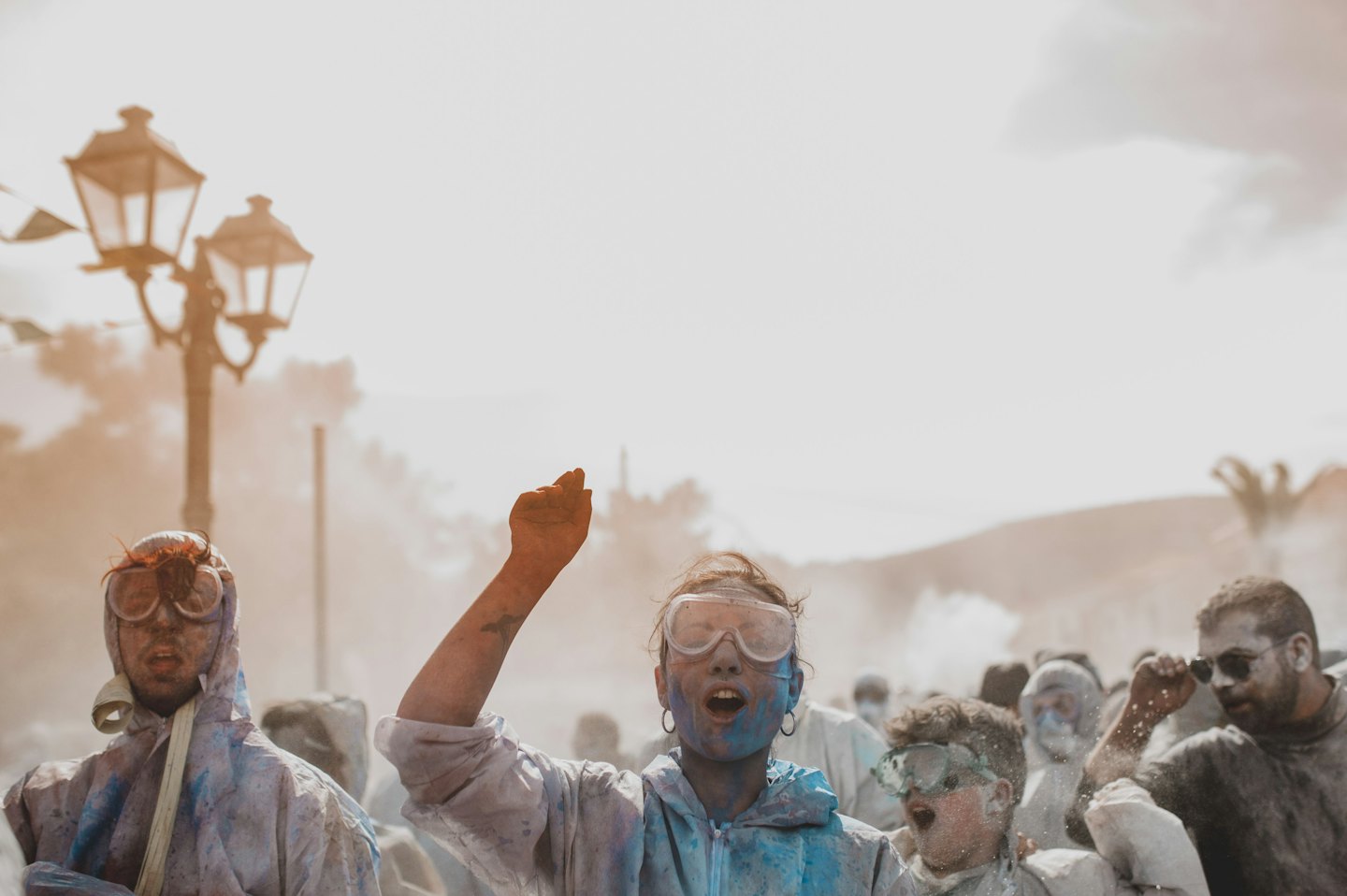 Young people covered in colorful powder celebrate at an outdoor festival.