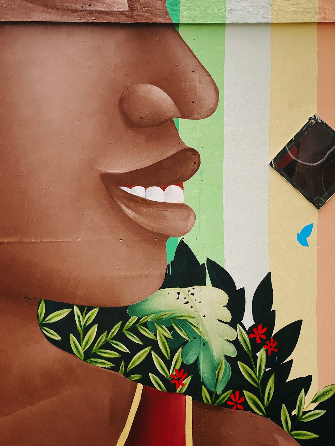 Colorful mural of a smiling person surrounded by flowers.