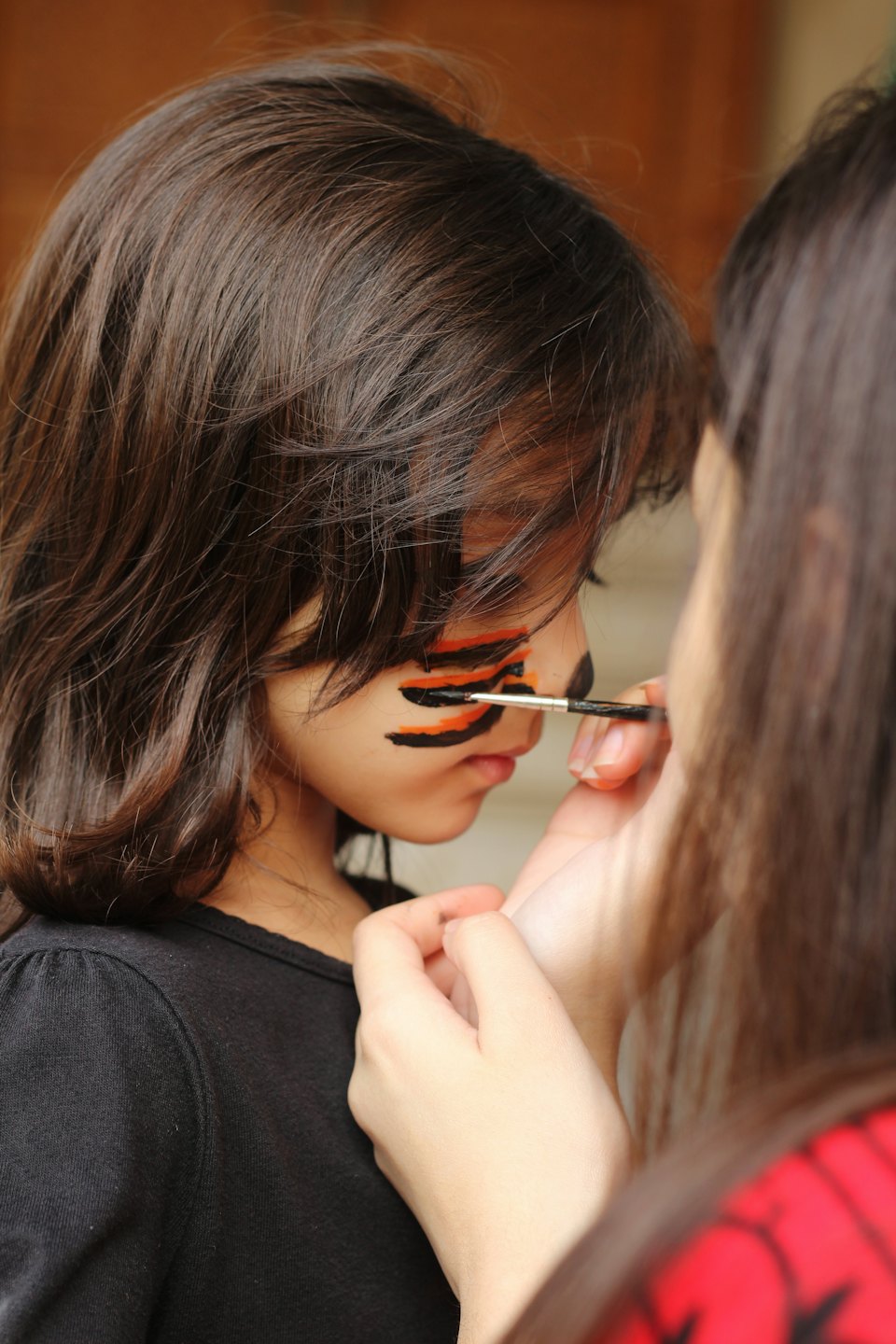 Child getting face painted like a tiger.